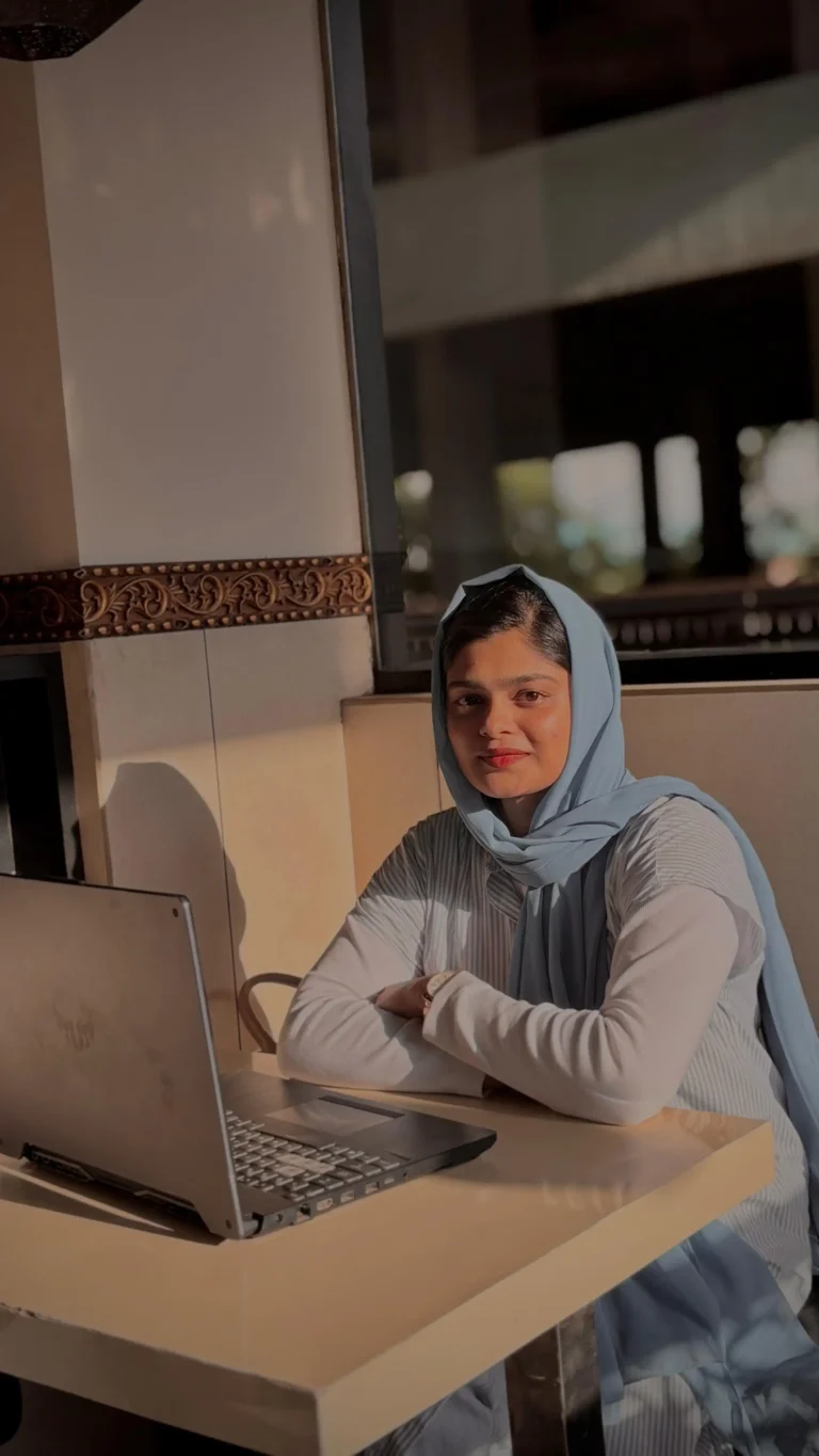 freelance digital marketing analyst in Malappuram sits at a table in frond of laptop, smiling and looking directly at camera